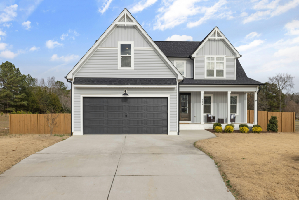 Bright, newly built two-story home with a welcoming front porch on a sunny day